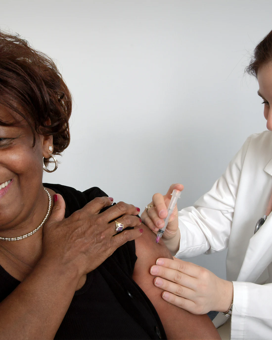 Smiling patient receiving a shot from a provider